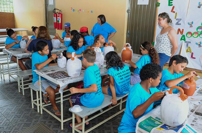 Acadêmicos auxiliam crianças em pintura de vasos