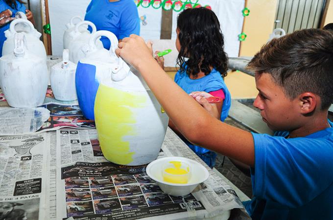 Acadêmicos auxiliam crianças em pintura de vasos