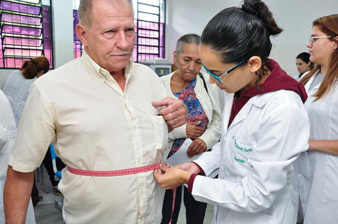 Estudante de Nutrição retirando medida da circunferência abdominal