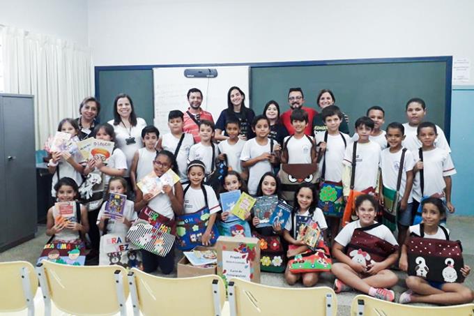 Crianças com as bolsas e os demais envolvidos no projeto