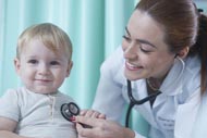 Pediatra sorridente examina um bebê com estetoscópio.