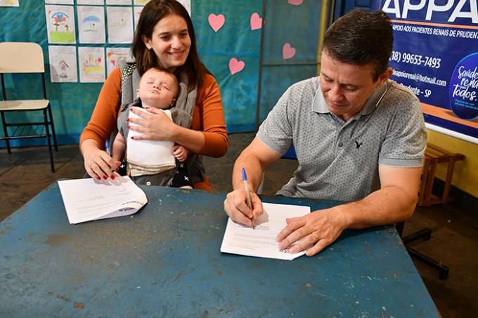 Assinatura do convênio por Bárbara, com o filho Francisco (dormindo) e Dr. Adilson